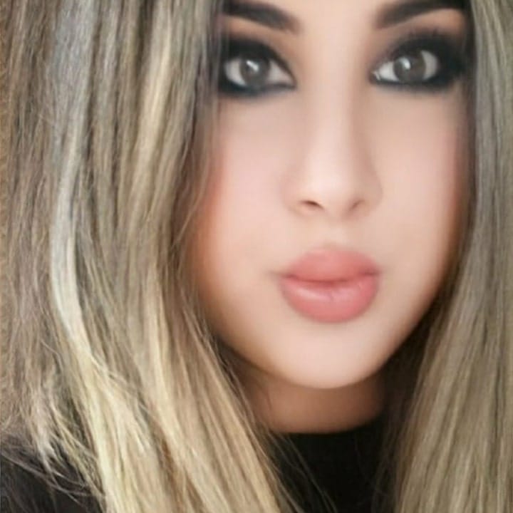 Close-up of a woman with smoky eye makeup and nude pink lips looking at the camera.